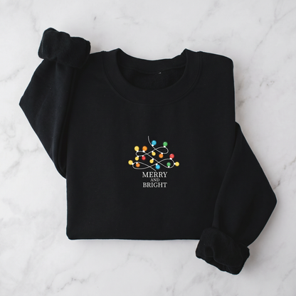 A black sweater with a white and colorful Christmas-themed design and the text "MERRY BRIGHT" printed on it.