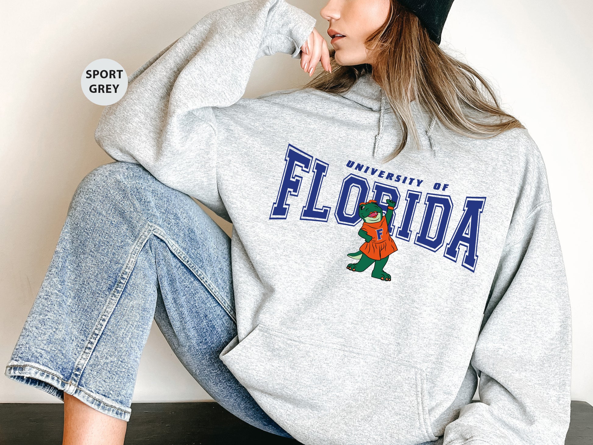 a woman sitting on the ground wearing a sweatshirt