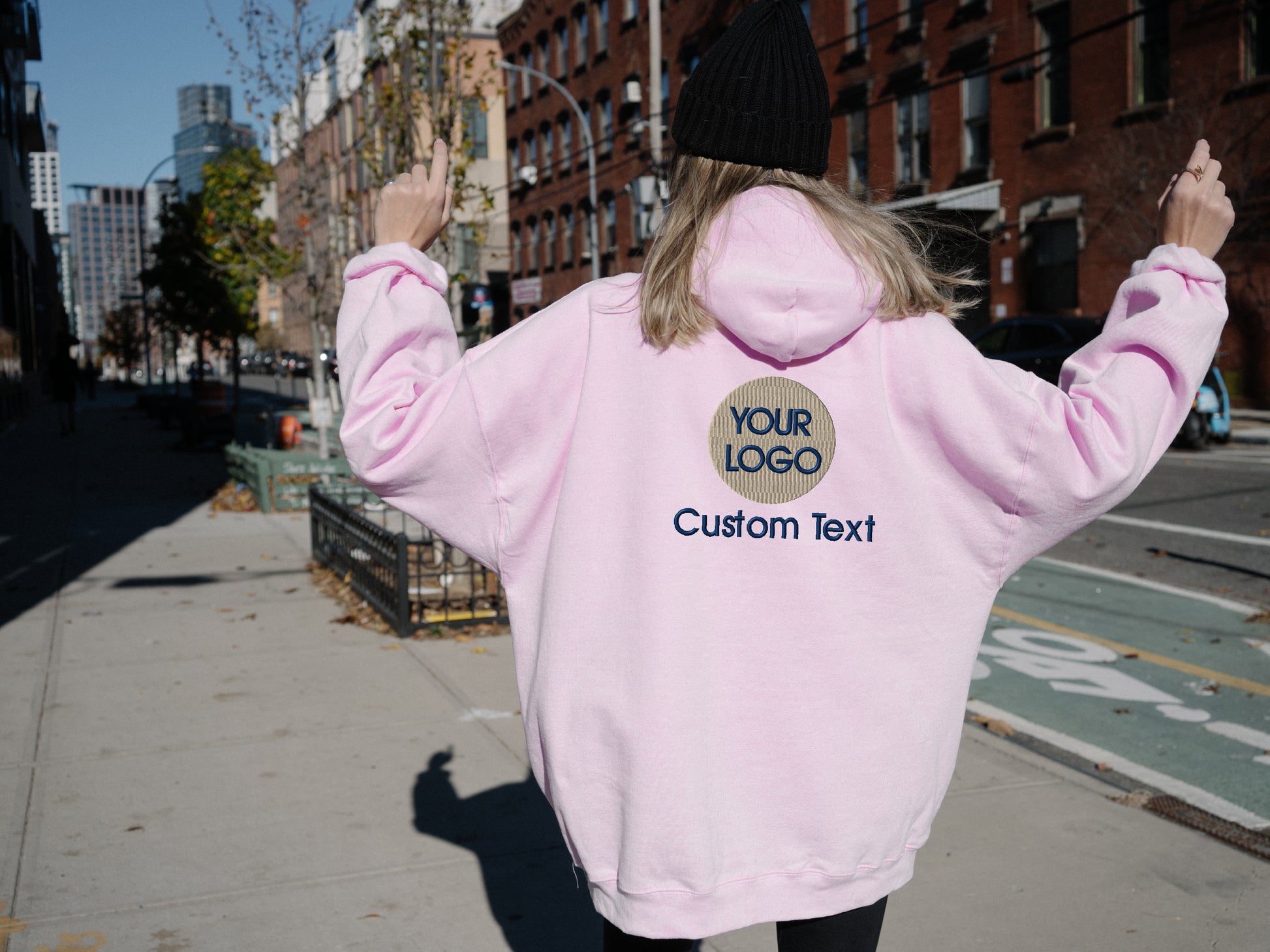 a woman in a pink hoodie is walking down the street