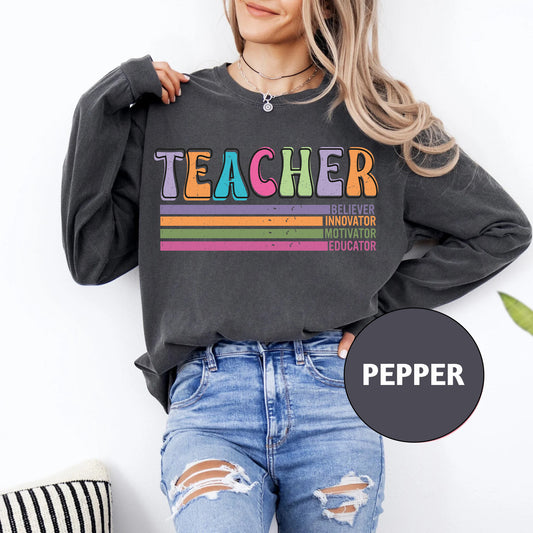 a woman wearing a teacher sweatshirt and ripped jeans