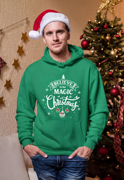 A man wearing a green hoodie with a Santa hat and a Christmas tree in the background.