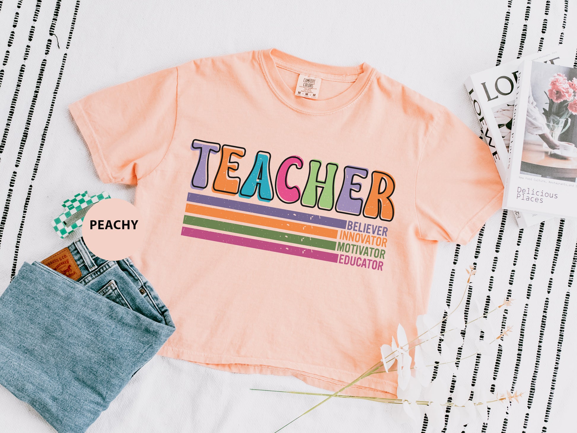 a t - shirt that says teacher on it next to a pair of jeans