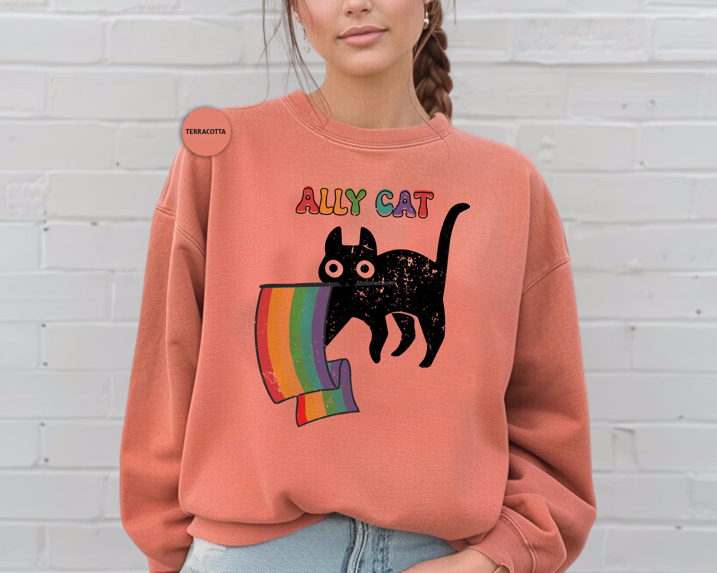 a woman wearing an orange sweatshirt with a black cat on it