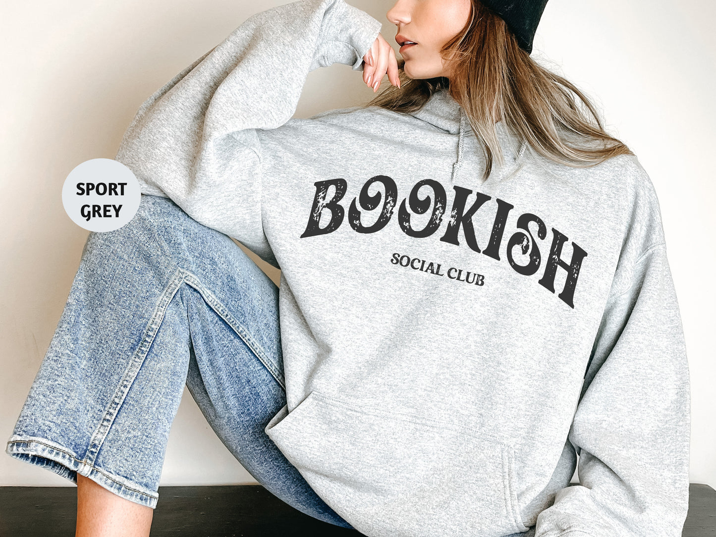 a woman sitting on the floor wearing a bookish sweatshirt