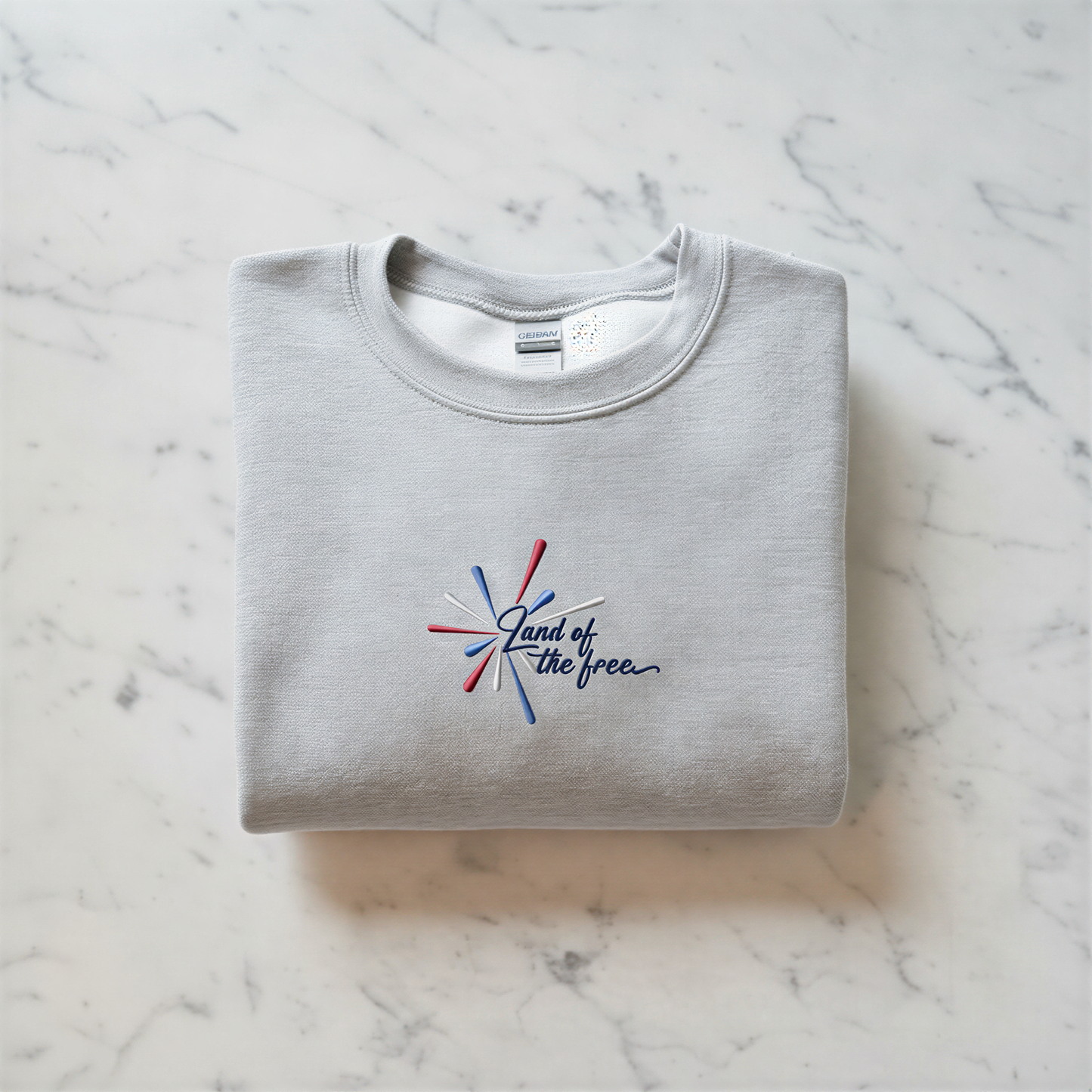 A gray sweatshirt with a red, white, and blue embroidered design on the front, along with the text "Land of the free" printed on it.