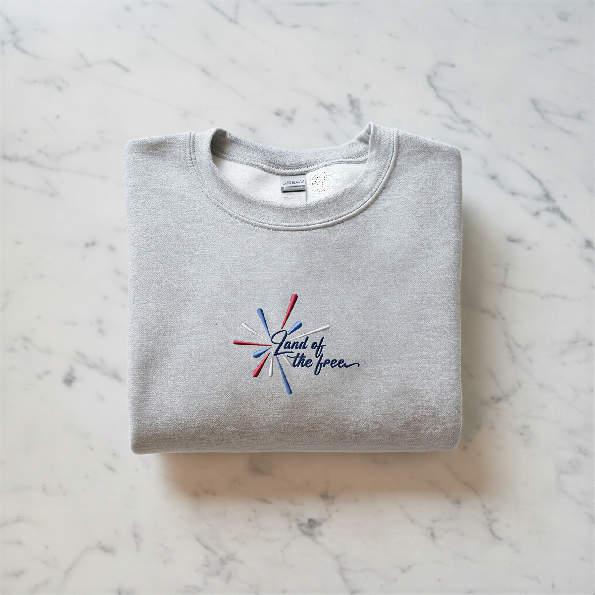 A gray sweatshirt with a red, white, and blue embroidered design on the front, along with the text "Land of the free" printed on it.