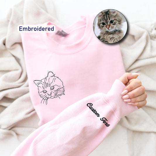 a person holding a pink sweater with a picture of a cat on it
