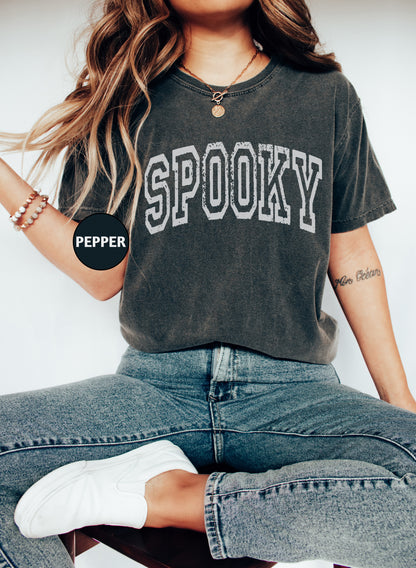 a woman sitting on a stool wearing a shirt that says spooky