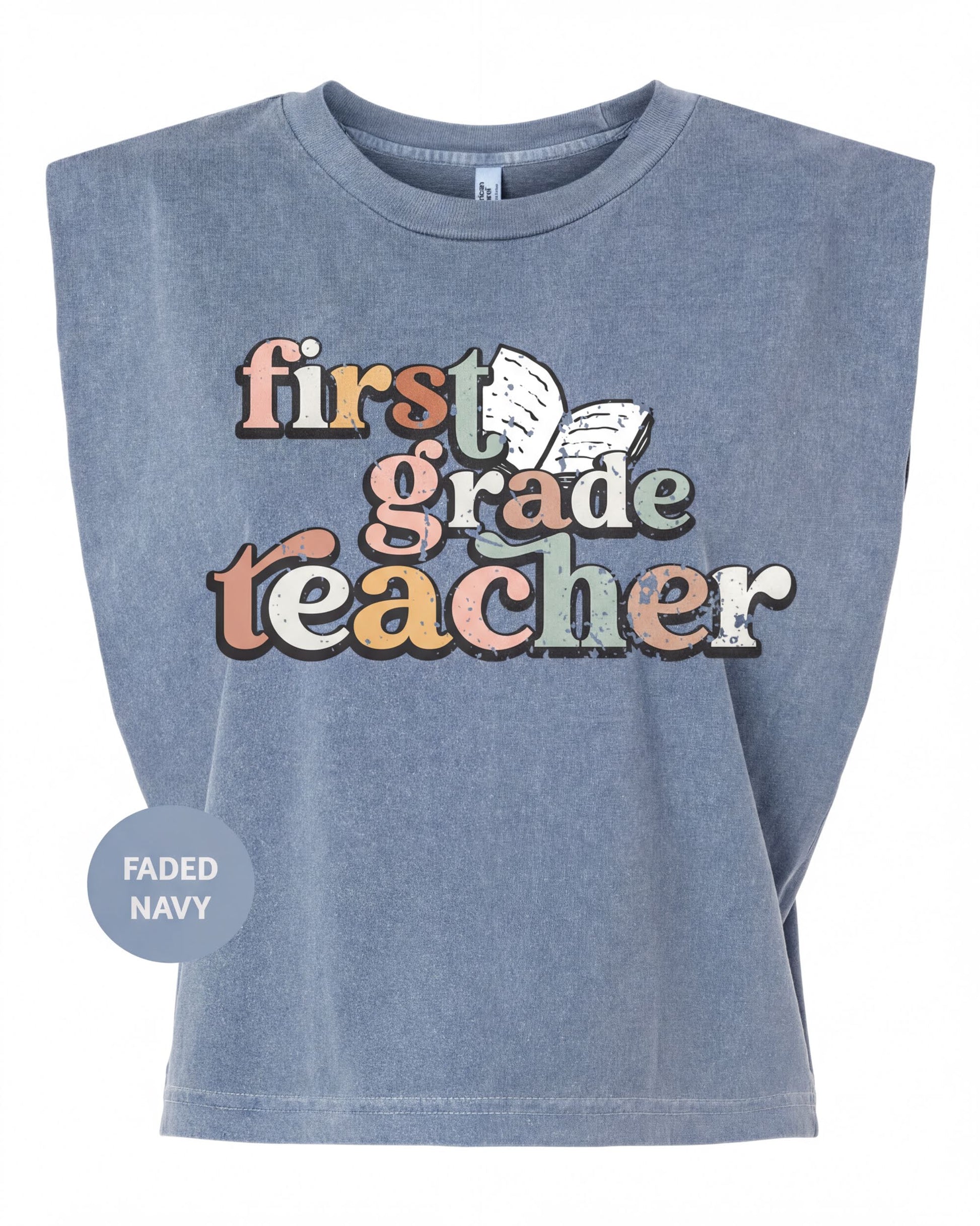 A gray t-shirt with the text "first grade teacher" printed on it in a colorful, retro-style font.
