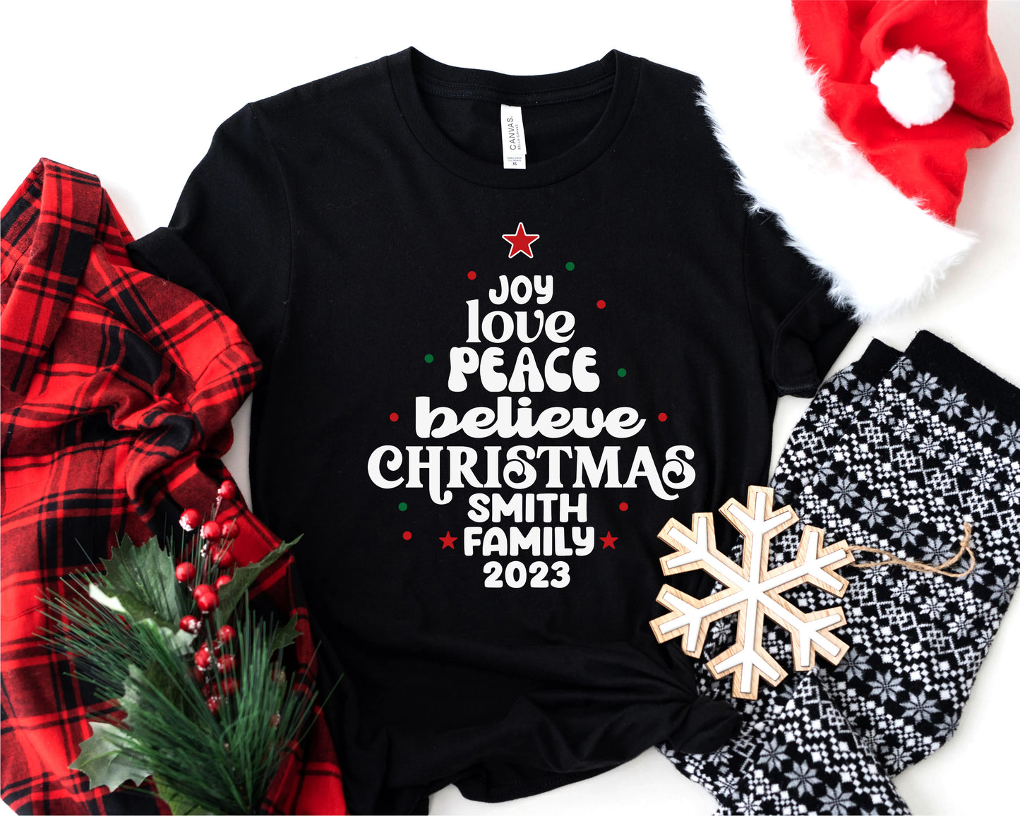 A black t-shirt with a Christmas-themed design, a red and black plaid shirt, a pair of black and white patterned pants, a red Santa hat, and a snowflake ornament.