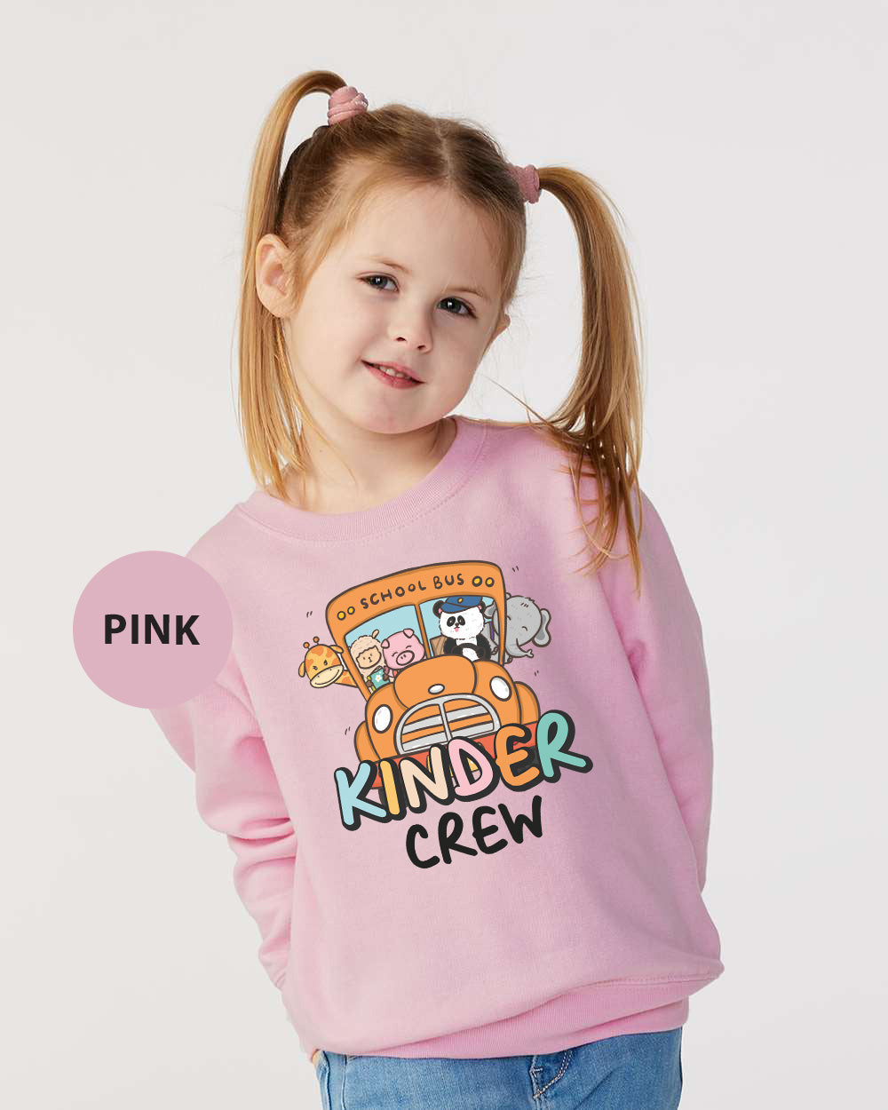 a little girl wearing a pink sweater with a school bus on it