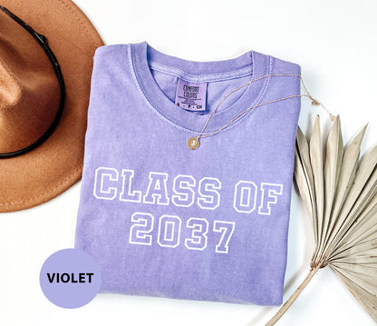 a purple shirt that says class of 202 next to a hat