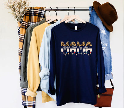 A collection of clothing items, including a navy blue long-sleeved shirt with a graphic design, a plaid shirt, a yellow shirt, and a pair of blue jeans, are hanging on a clothing rack.