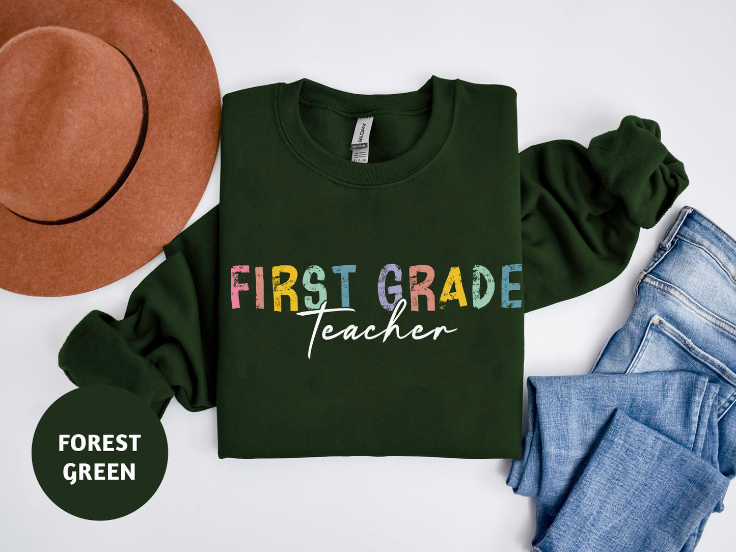 a green shirt that says first grade teacher next to a hat and jeans