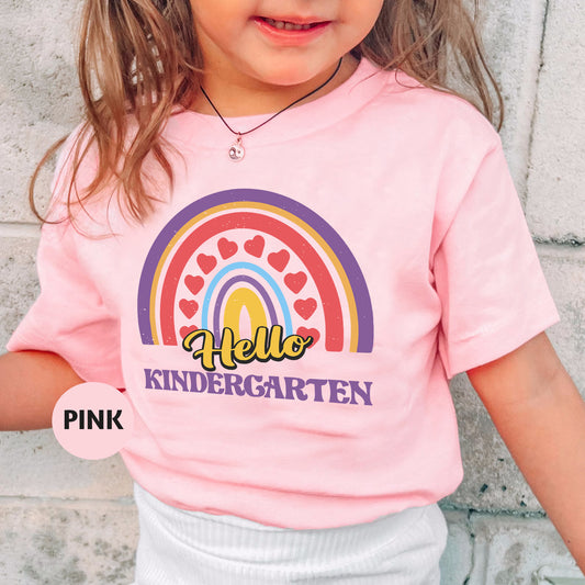 a little girl wearing a pink shirt with a rainbow on it