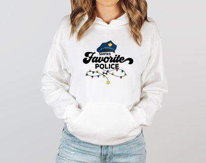 A woman wearing a white hoodie with a graphic design that says "Santa's Favorite Police" and a police hat.