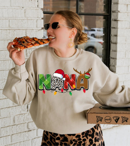 A woman wearing a sweater with the word "NANA" on it is eating a slice of pizza.