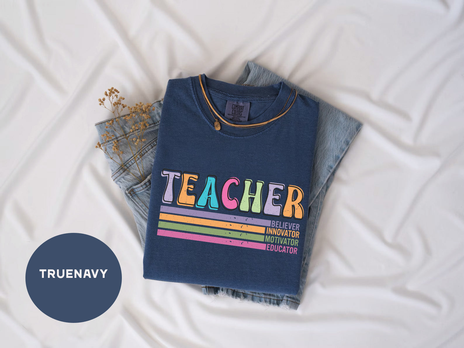 a t - shirt that says teacher on it next to a pair of jeans