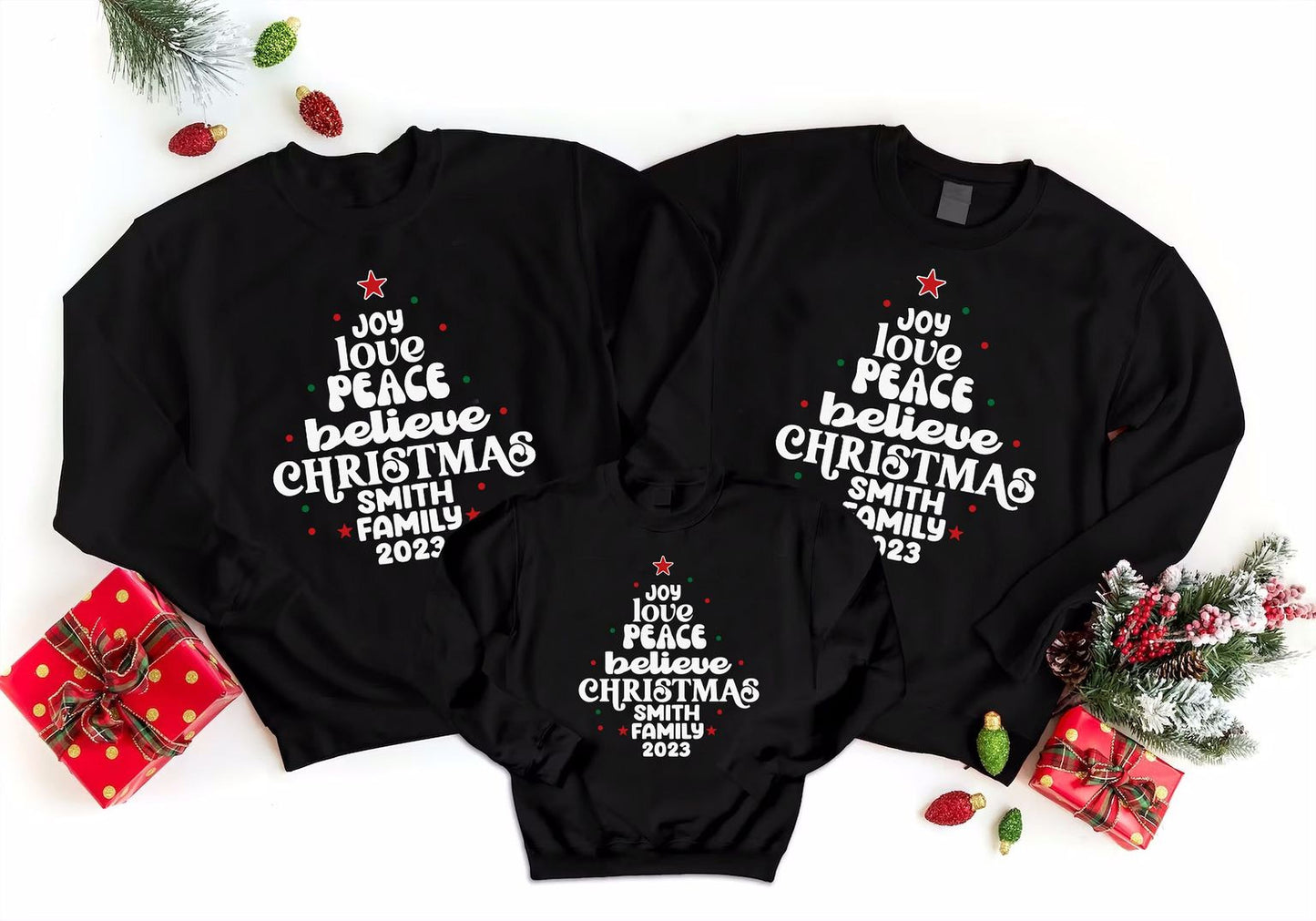 three black sweatshirts with white text and Christmas tree designs, along with some Christmas decorations and gifts.
