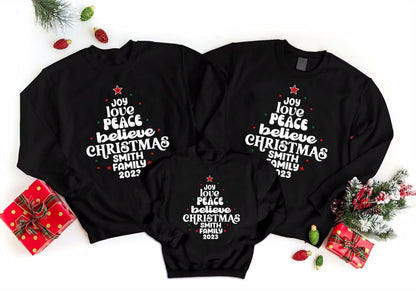 three black sweatshirts with white text and Christmas tree designs, along with some Christmas decorations and gifts.
