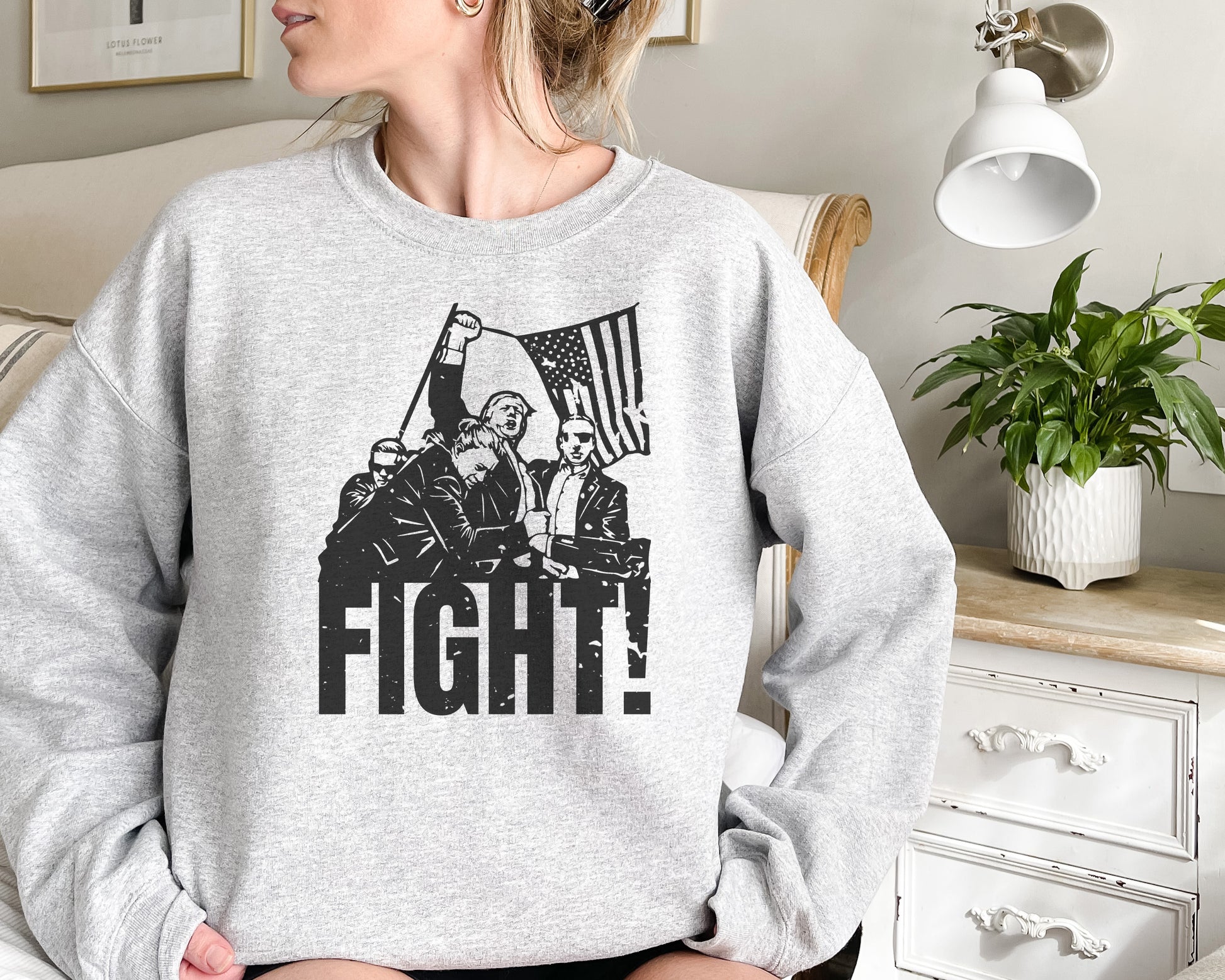 a woman sitting on a couch wearing a sweatshirt that says fight