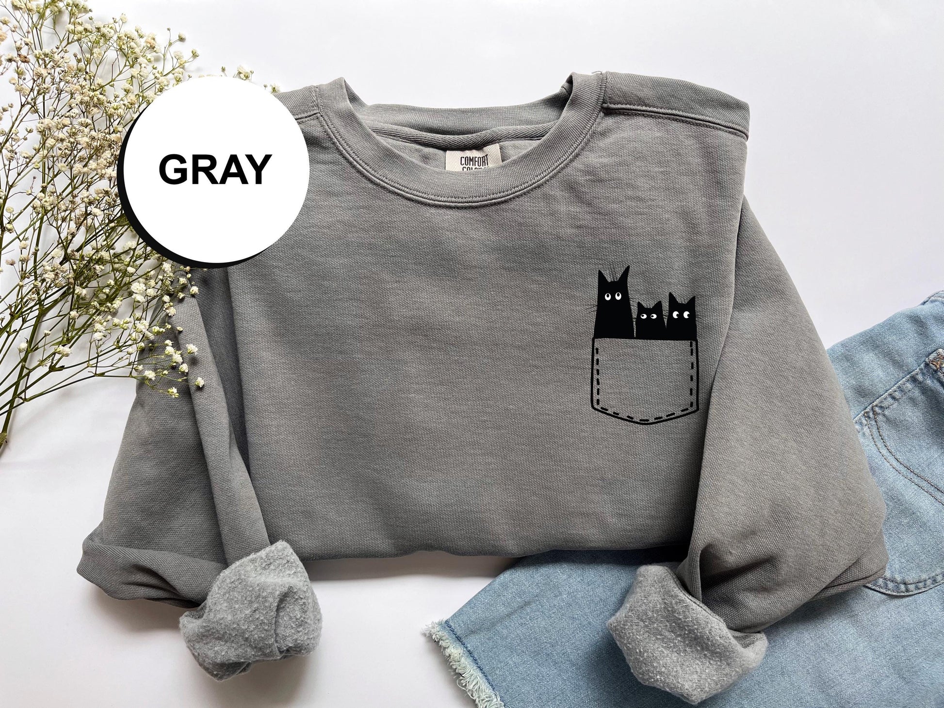 a gray sweatshirt with a black cat in the pocket