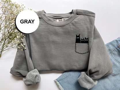 a gray sweatshirt with a black cat in the pocket