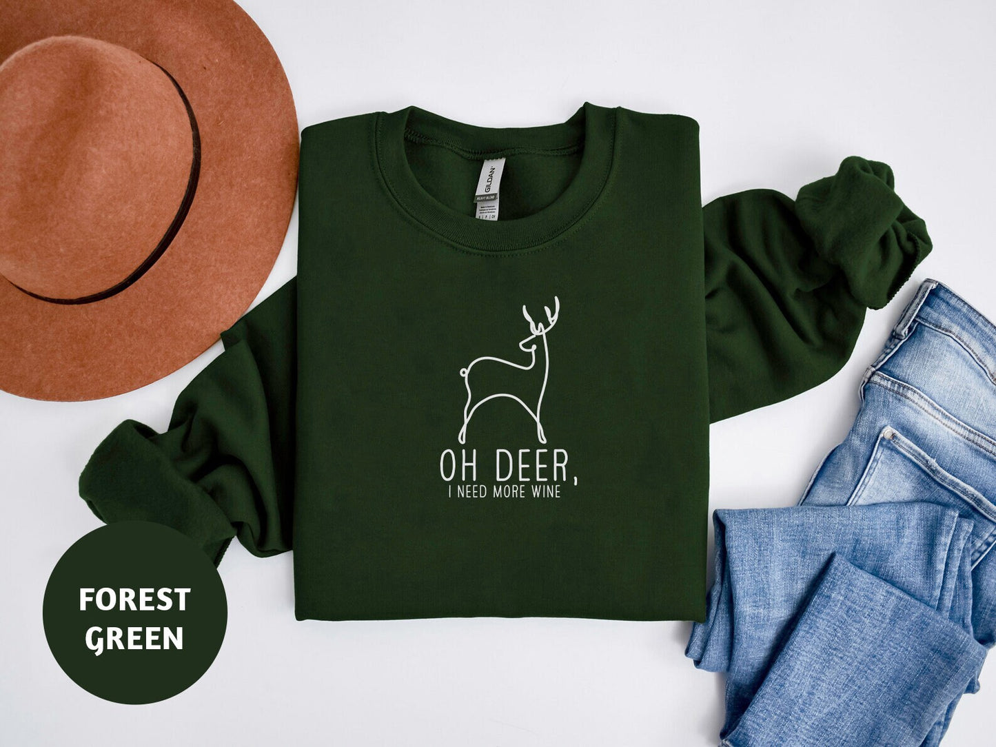 a green shirt with a deer on it next to jeans and a hat