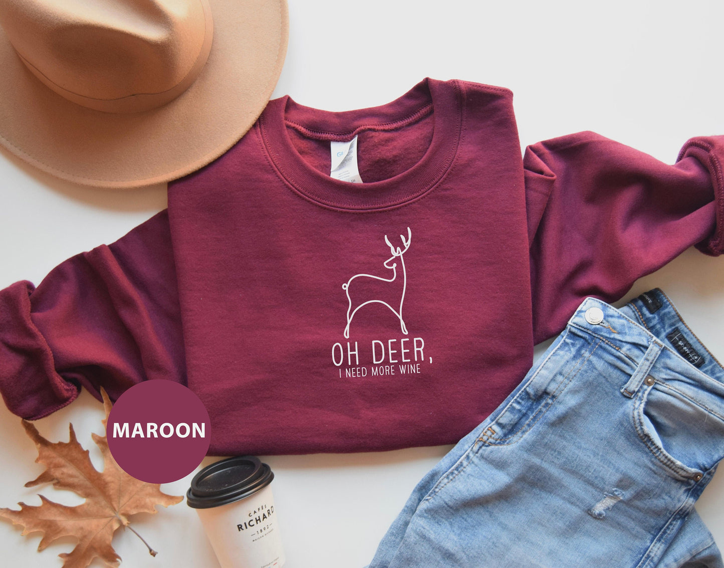 a maroon shirt with a deer on it and a hat next to it