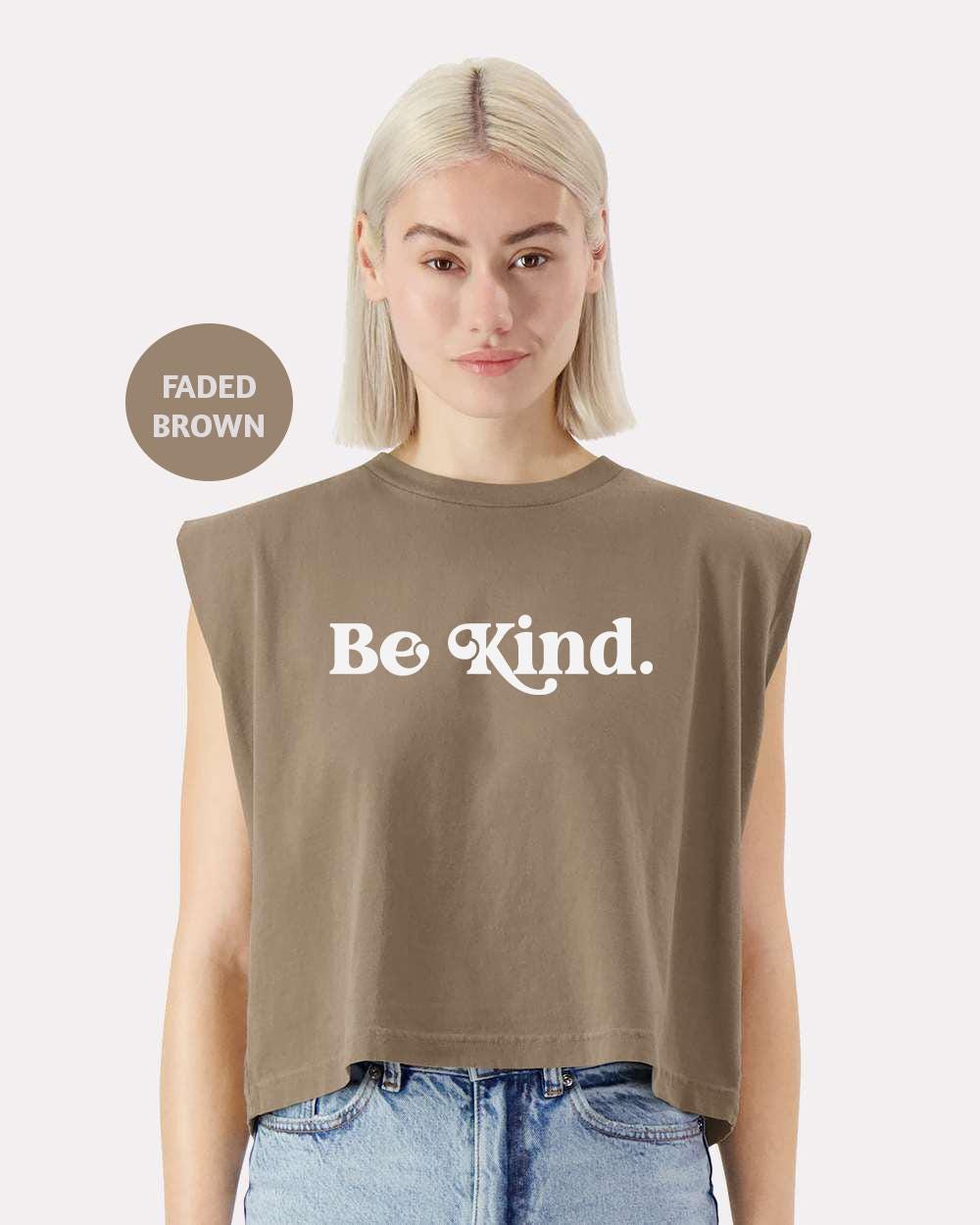 a woman with blonde hair wearing a crop top that says be kind