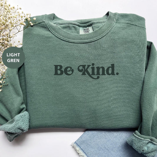 a green sweatshirt with the words be kind printed on it
