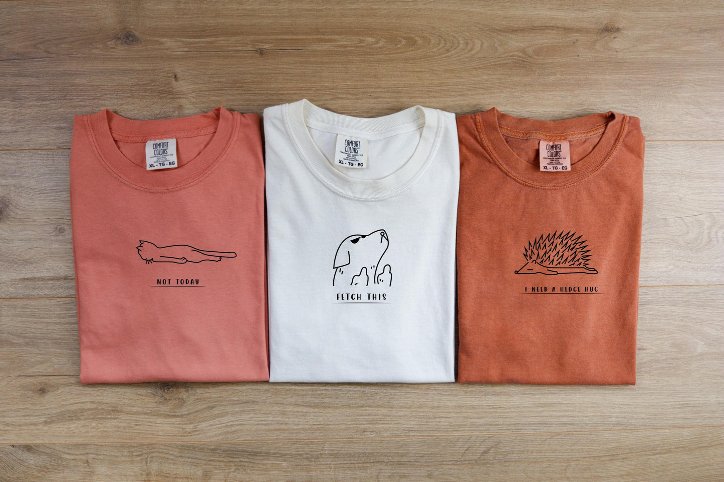 three t - shirts on a wooden surface with a tag