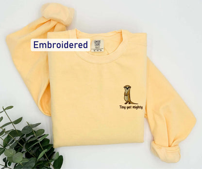 a yellow t - shirt with an embroidered meerkat on it