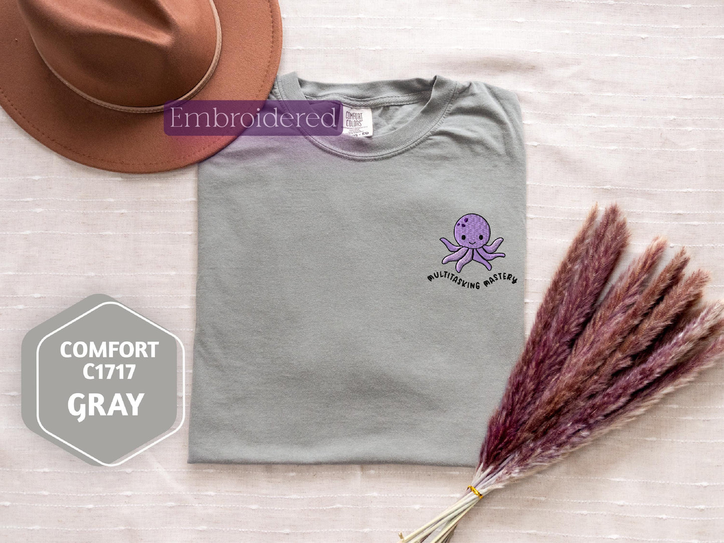 a hat, a t - shirt, and a purple flower on a bed