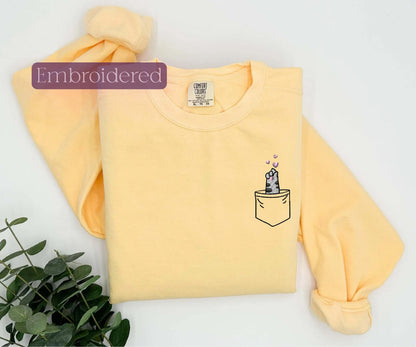 a yellow shirt with a picture of a cat in a pocket