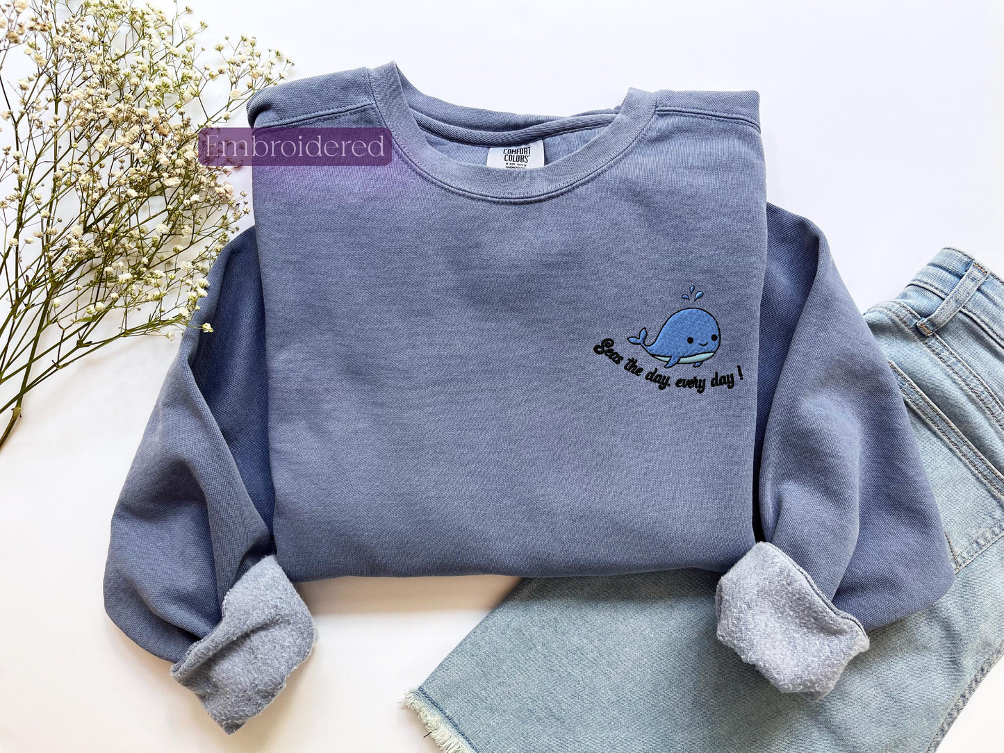 a blue sweater with a whale embroidered on it