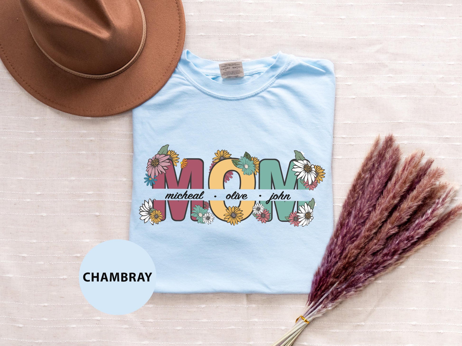 a t - shirt with the word mom printed on it next to a hat