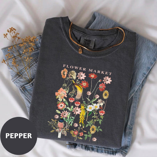 a flower market t - shirt laying on top of a bed