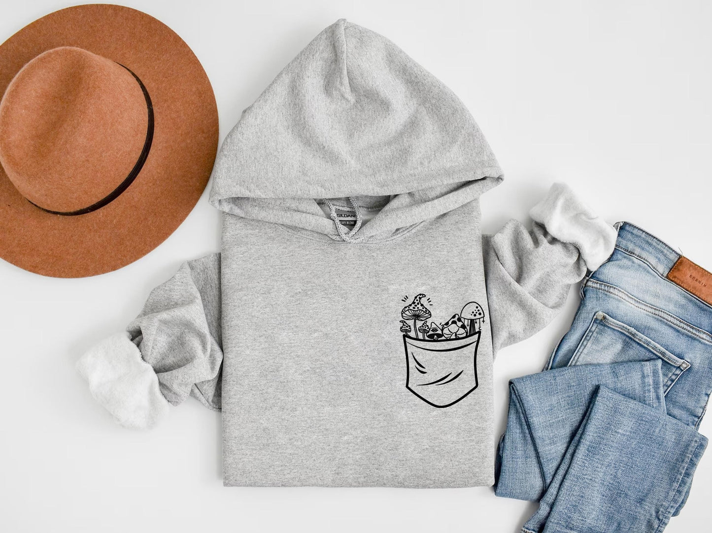 a hat, jeans, and sweatshirt on a white surface