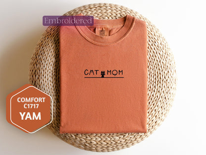 a cat mom t - shirt sitting on top of a wicker basket