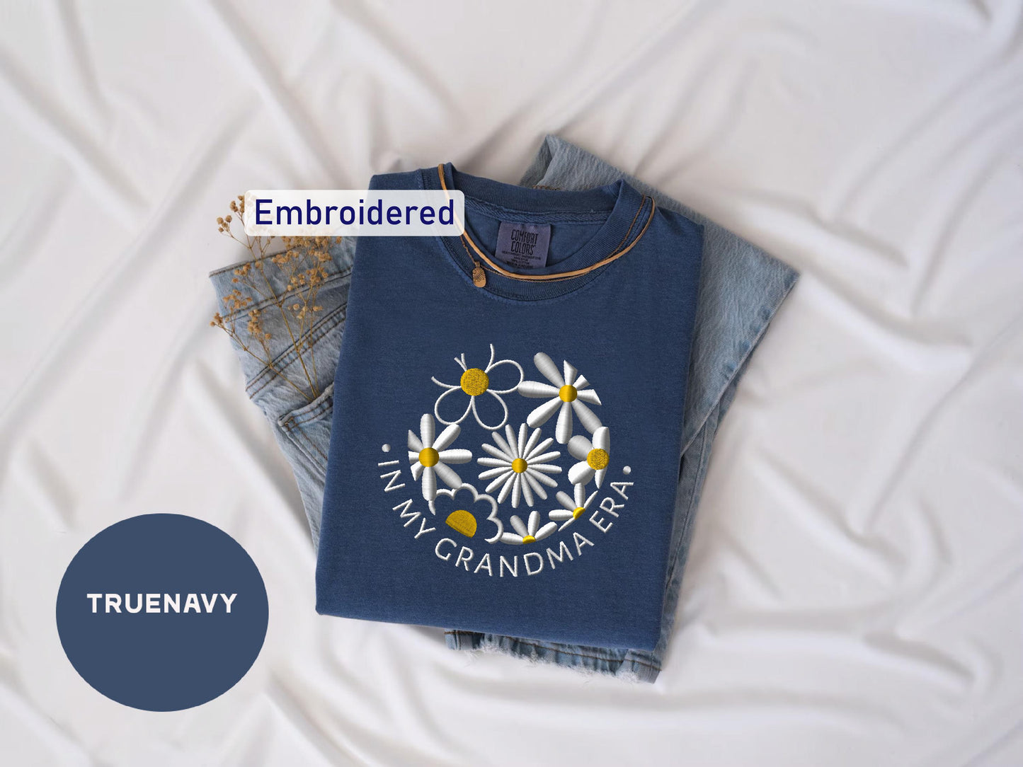 a blue t - shirt with a flower on it next to a pair of jeans
