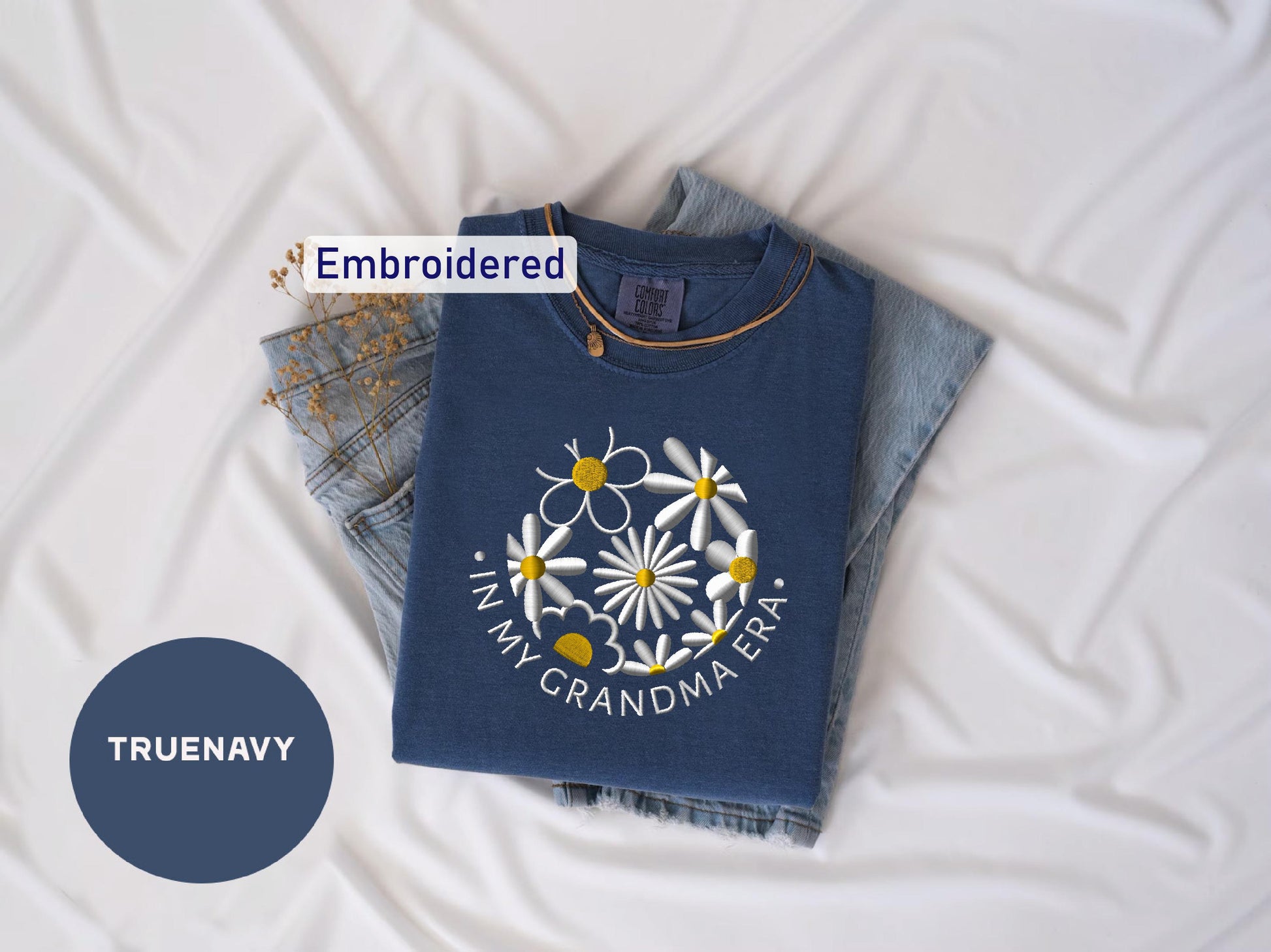 a blue t - shirt with a flower on it next to a pair of jeans