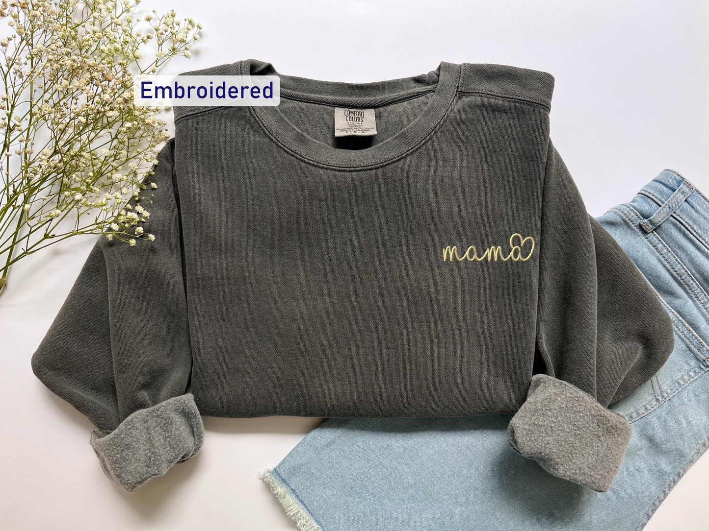 a gray shirt with a name on it next to a pair of jeans