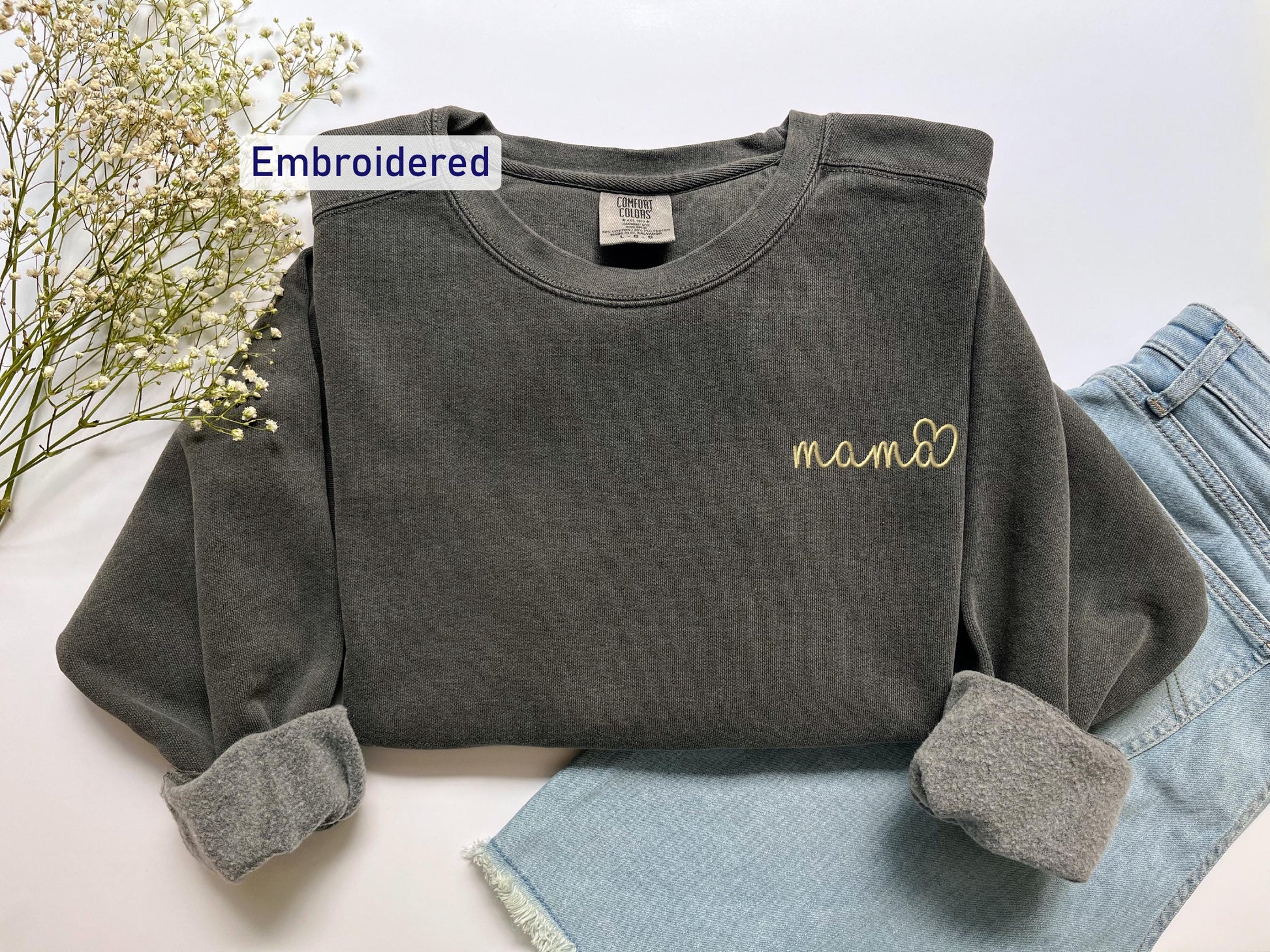 a gray shirt with a name on it next to a pair of jeans