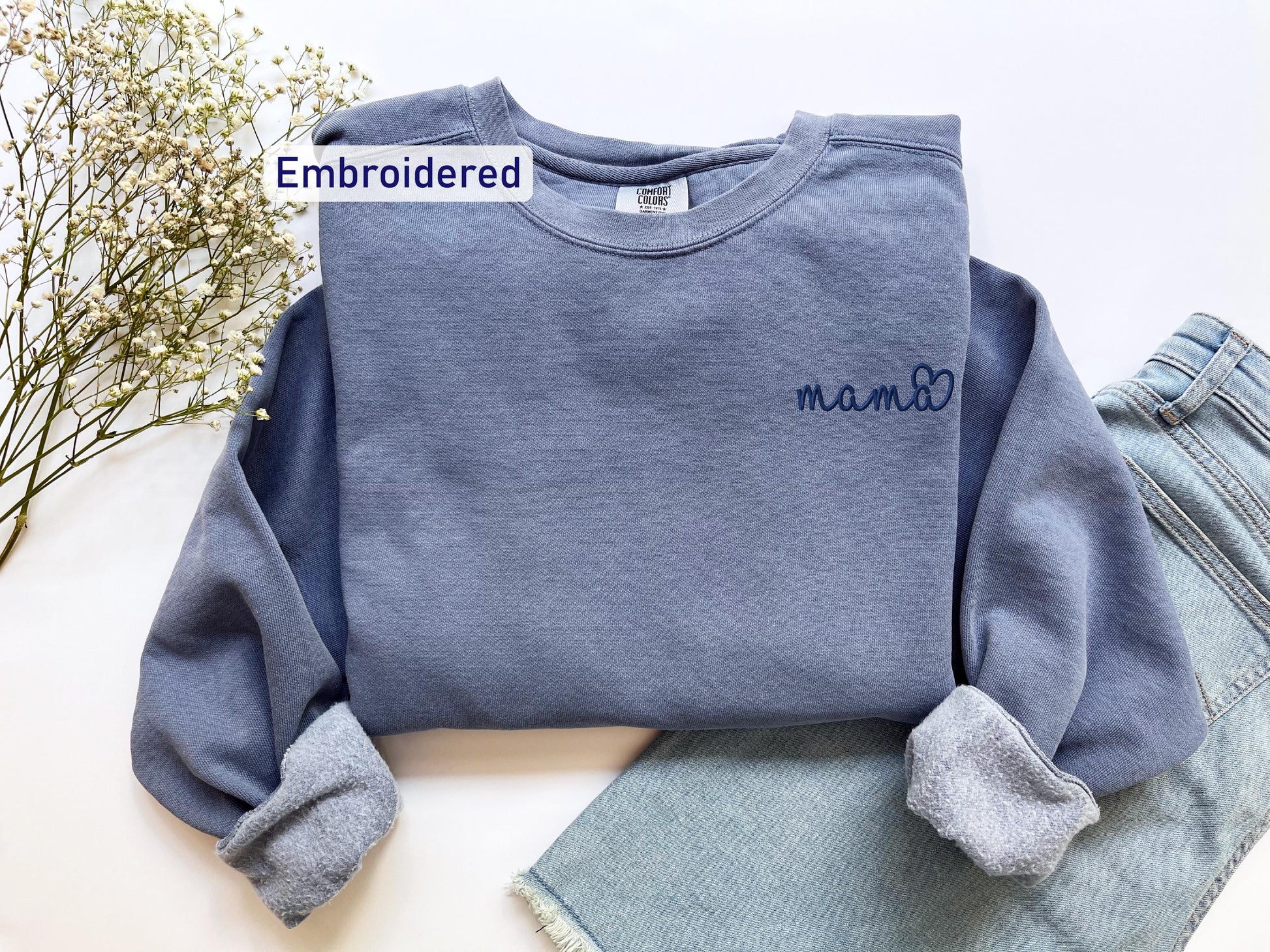 a blue sweatshirt with a name on it next to a pair of jeans