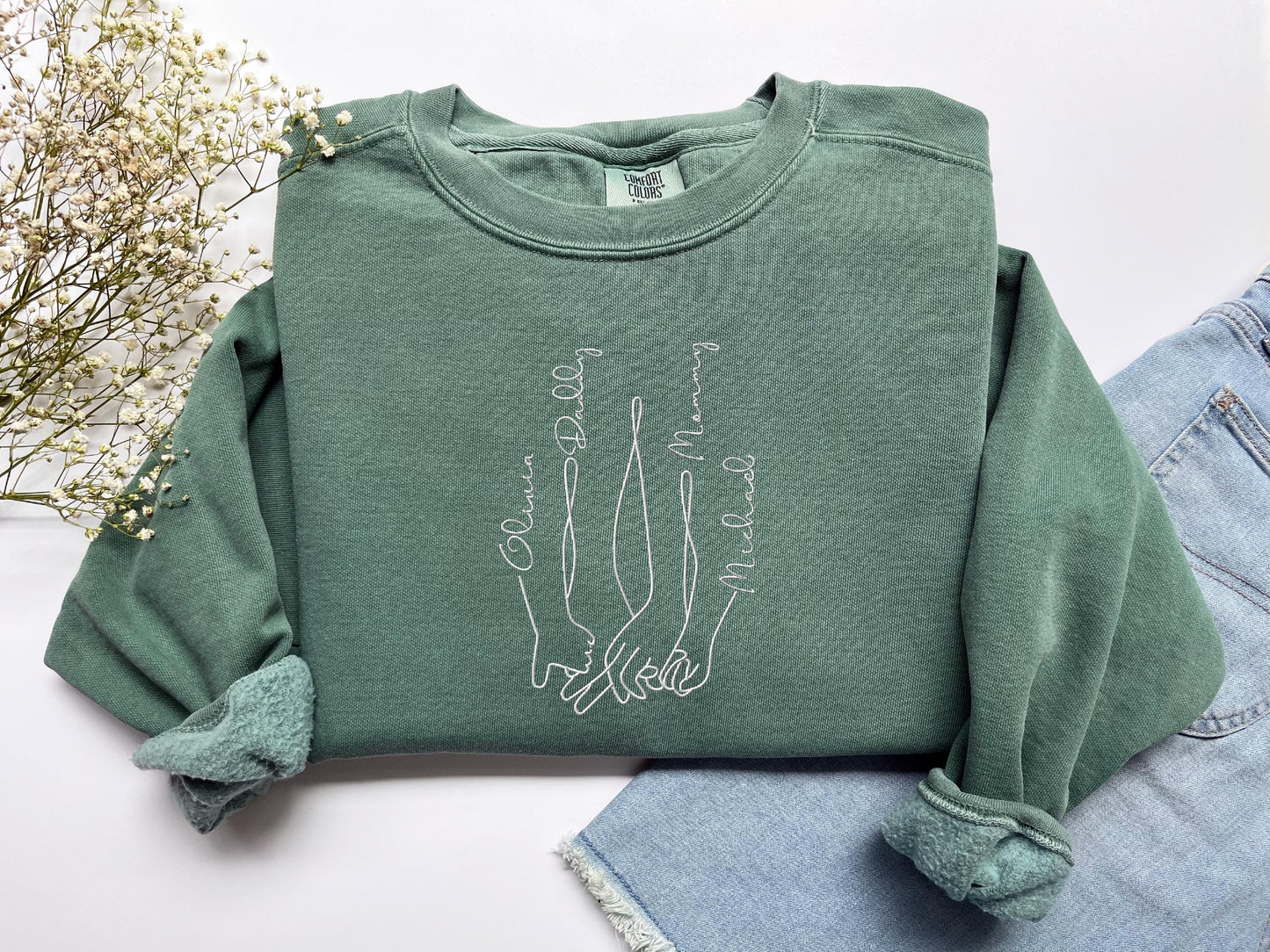 a pair of jeans and a green sweatshirt with a picture of two hands on it