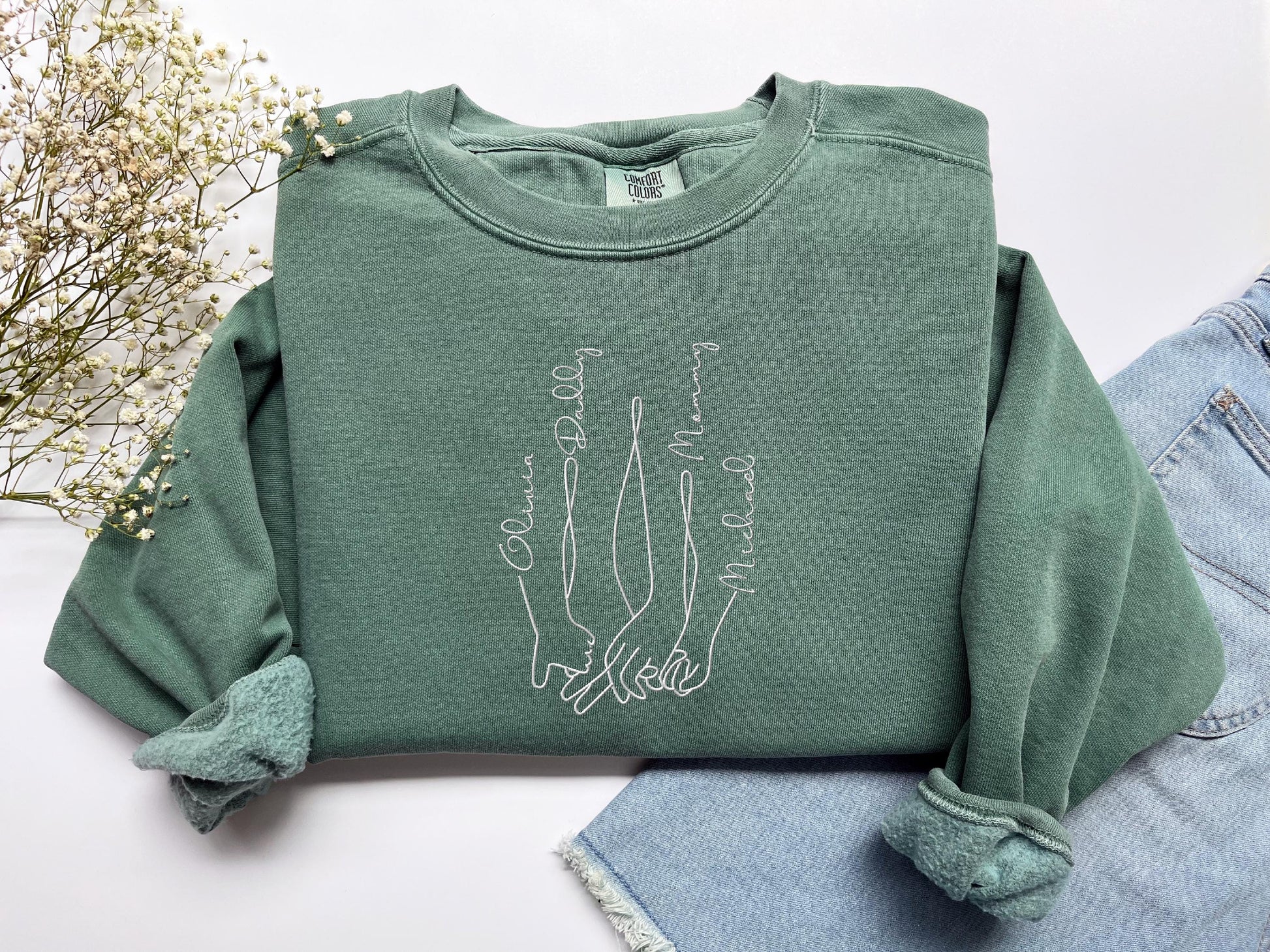 a pair of jeans and a green sweatshirt with a picture of two hands on it