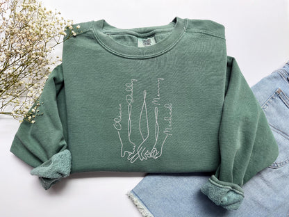 a pair of jeans and a green sweatshirt with a picture of two hands on it