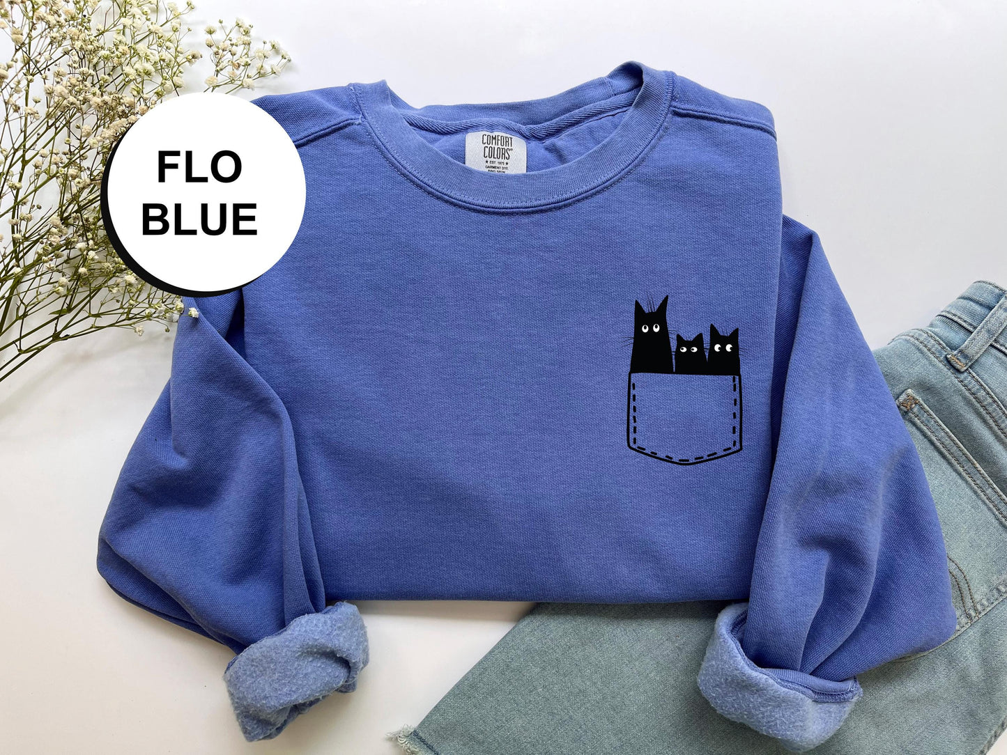 a blue sweatshirt with a black cat in a pocket
