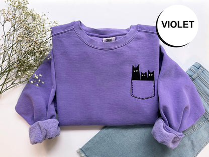 a purple shirt with a black cat in the pocket
